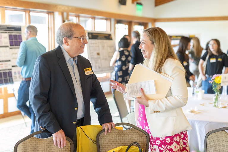 Retreat attendees talking with poster session in the background