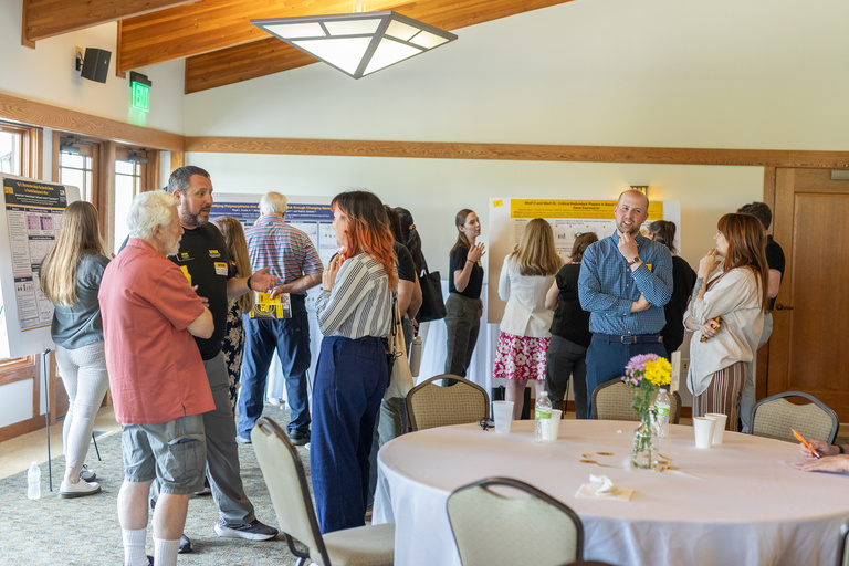 Retreat attendees talking, poster session in background