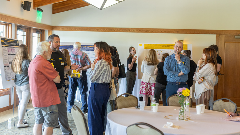 Retreat attendees talking, poster session in background